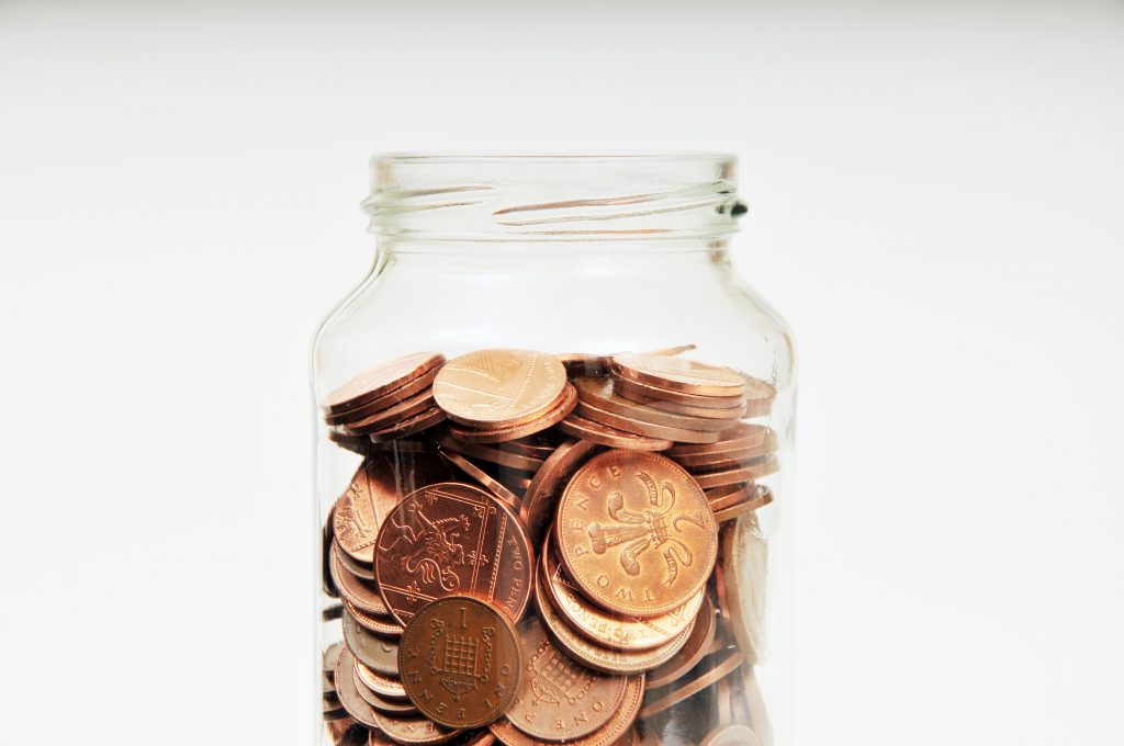 Glass jar nearly full of coins depicting end to rising wealth