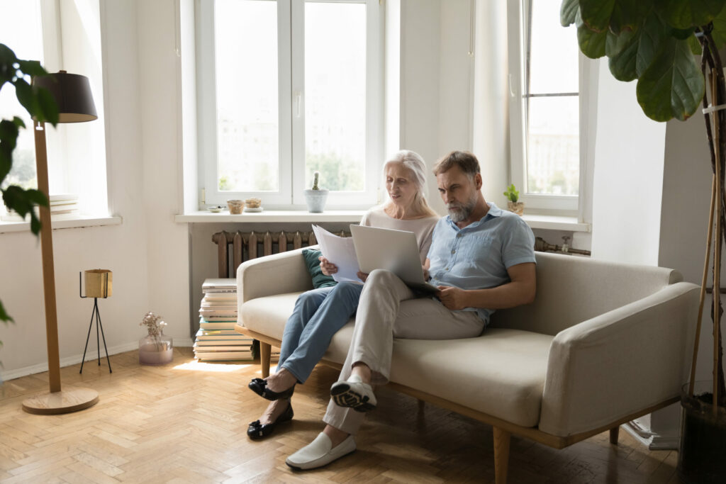 A mature couple sitting on sofa at home, checking paperwork, ensuring right protection is in place