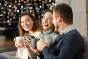 A couple of young women in a café laughing, one holding a coffee, talking about taking out a joint mortgage