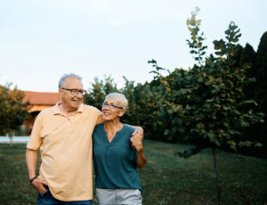 Happy senior couple enjoying while walking embraced in their backyard. Copy space.